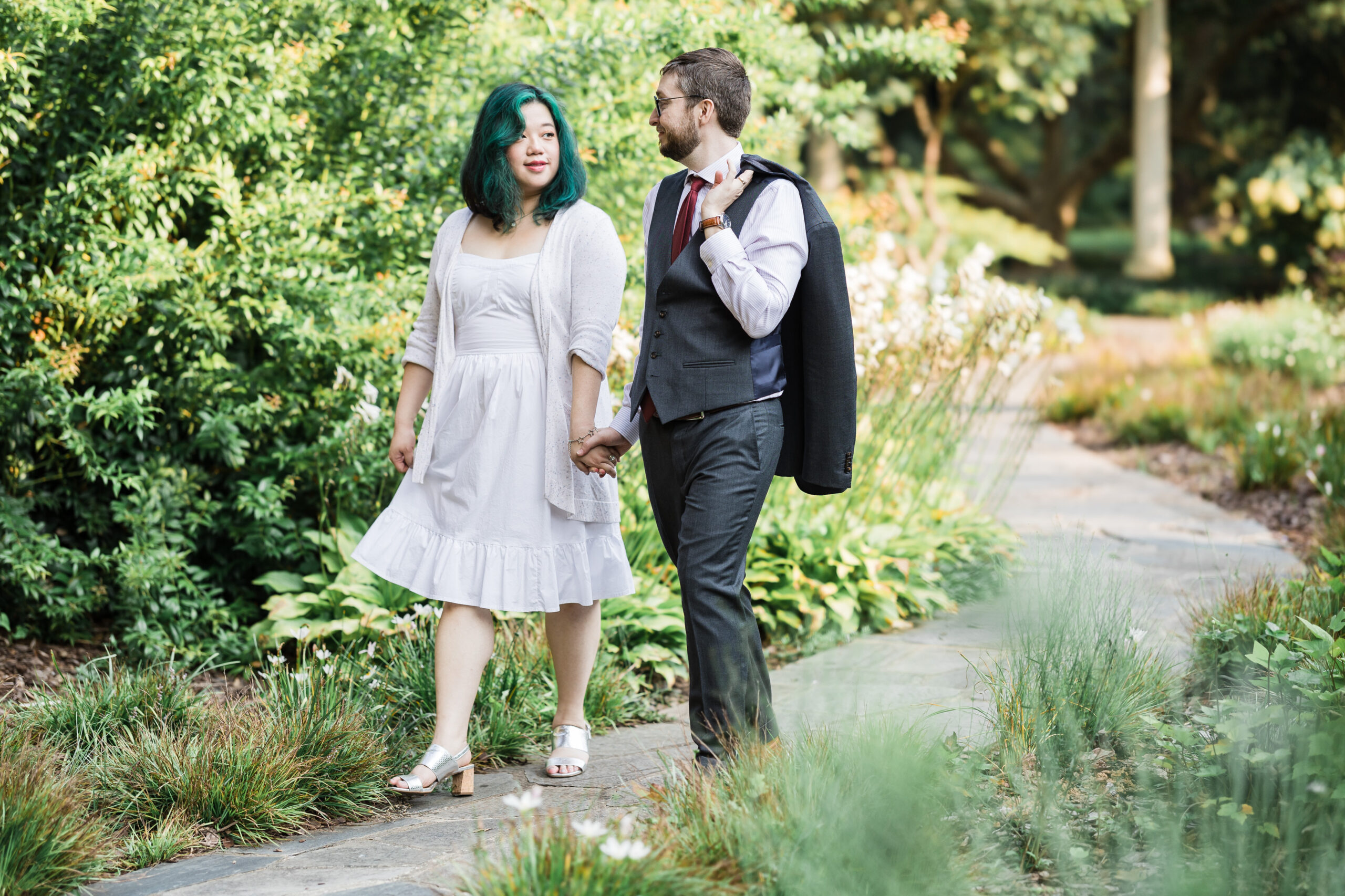 Bride and Groom walking hand in hand at a garden while look at each other