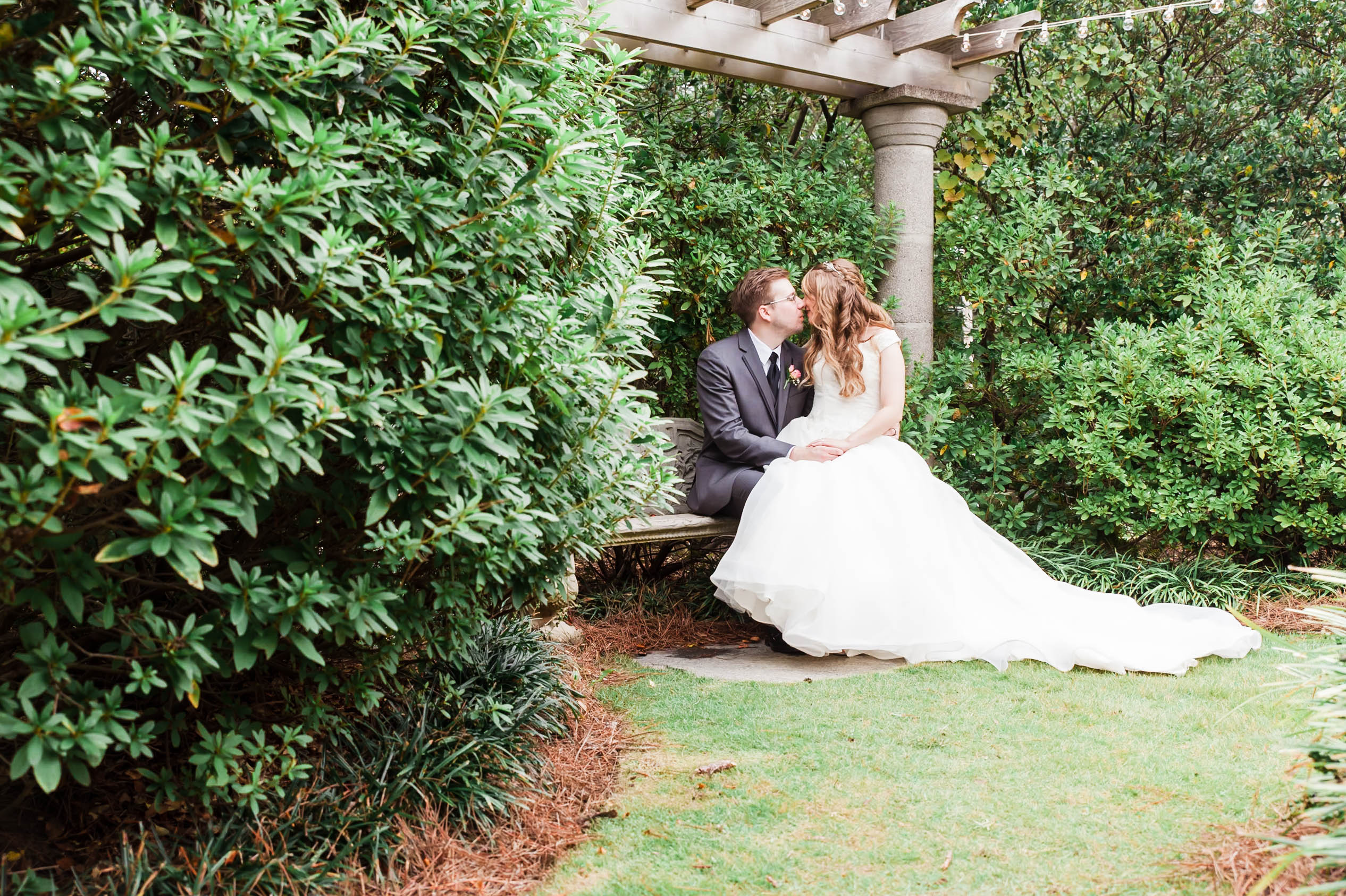bride and groom kiss at the garden filled with greenery
