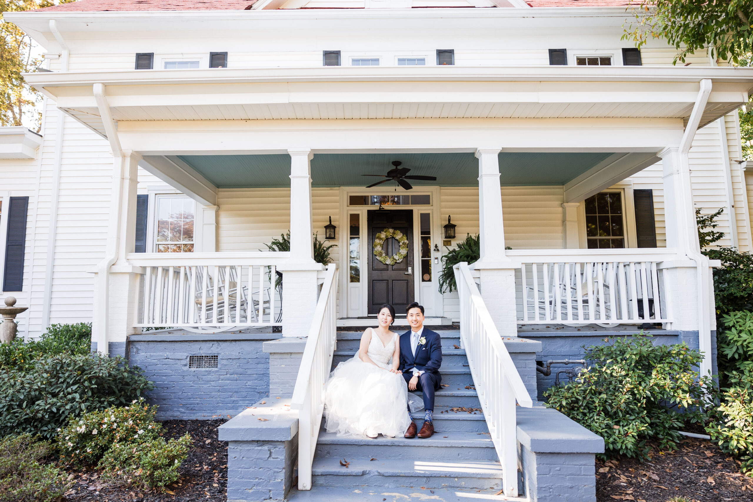 bride and groom sit beside each other on the steps of payne corley house