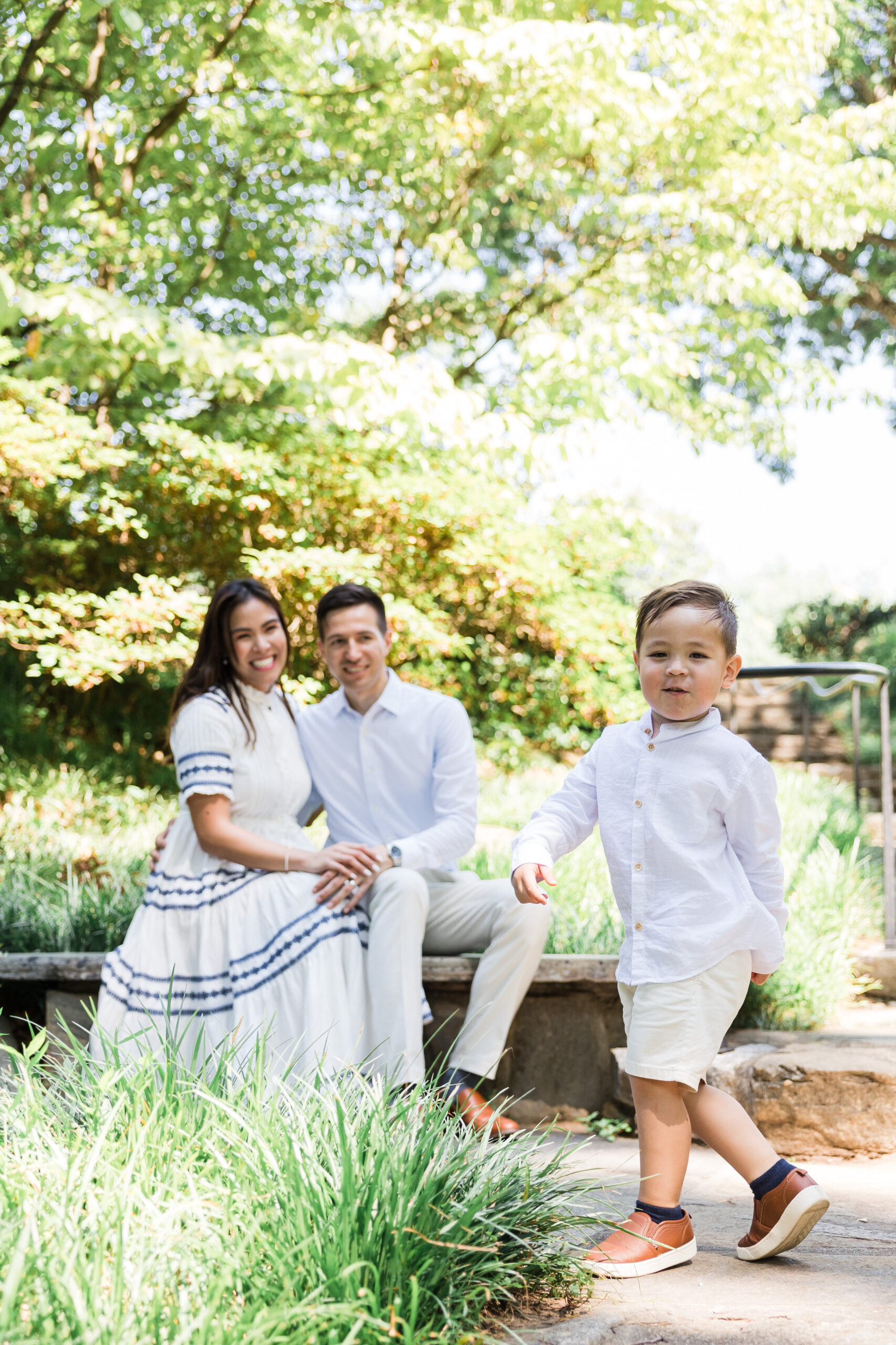 little boy skips while his parents are watching him smiling at the back