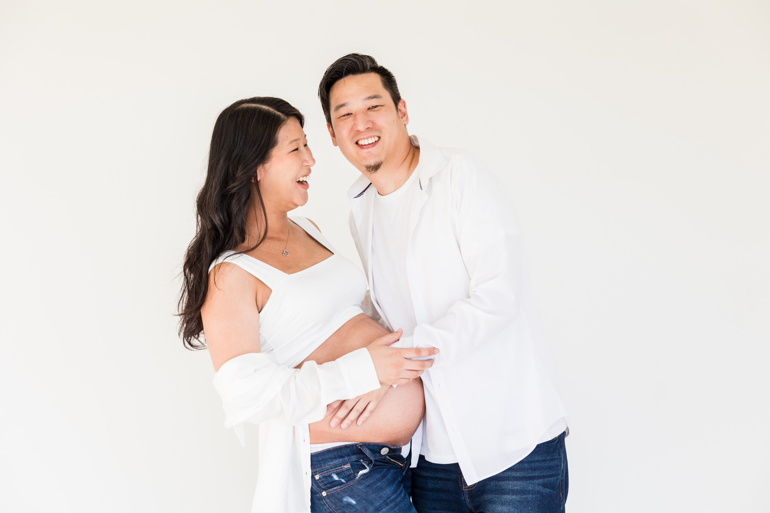 pregnant mom poses with dad while they're laughing