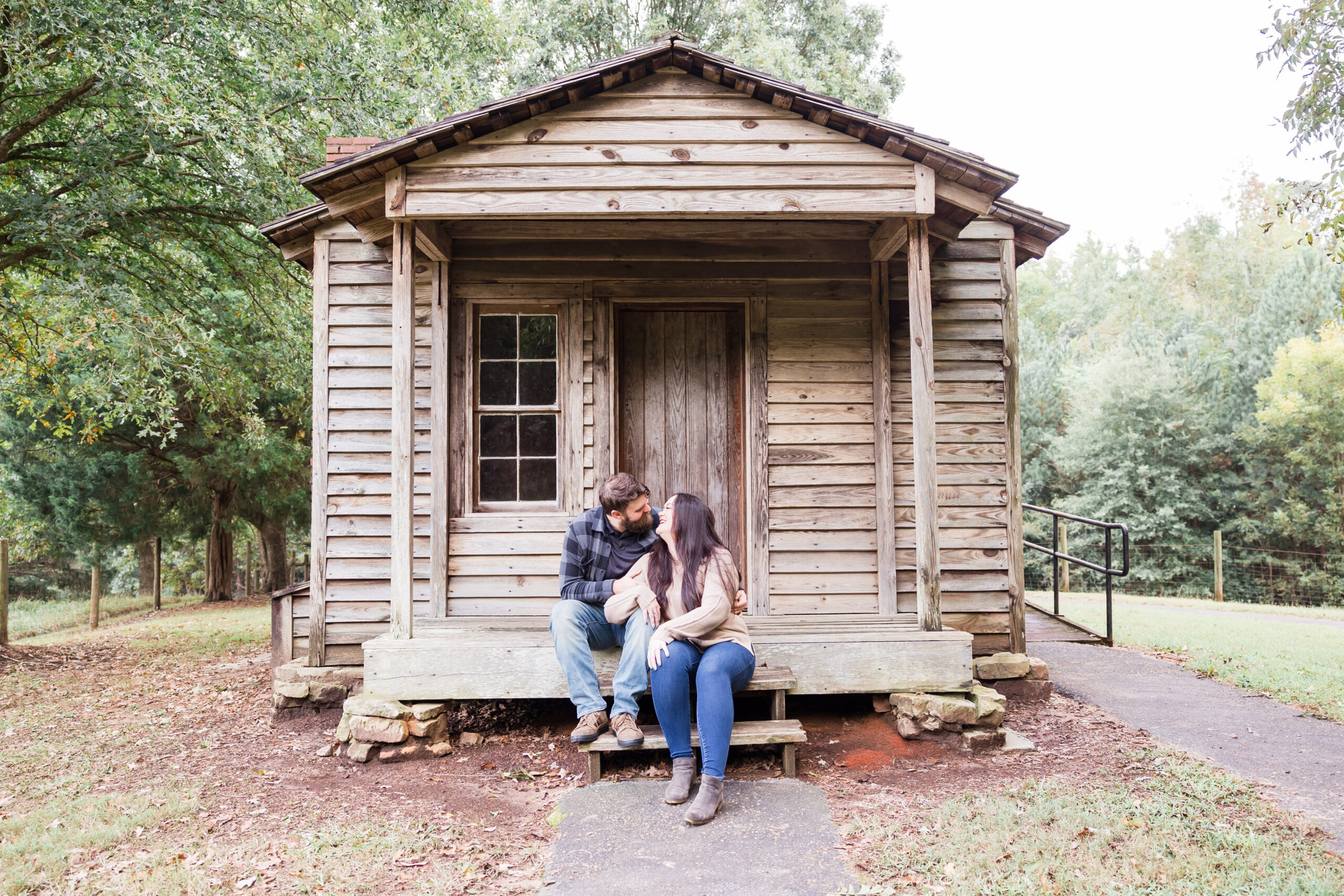 bride and groom sit and kiss in front of a small cottage