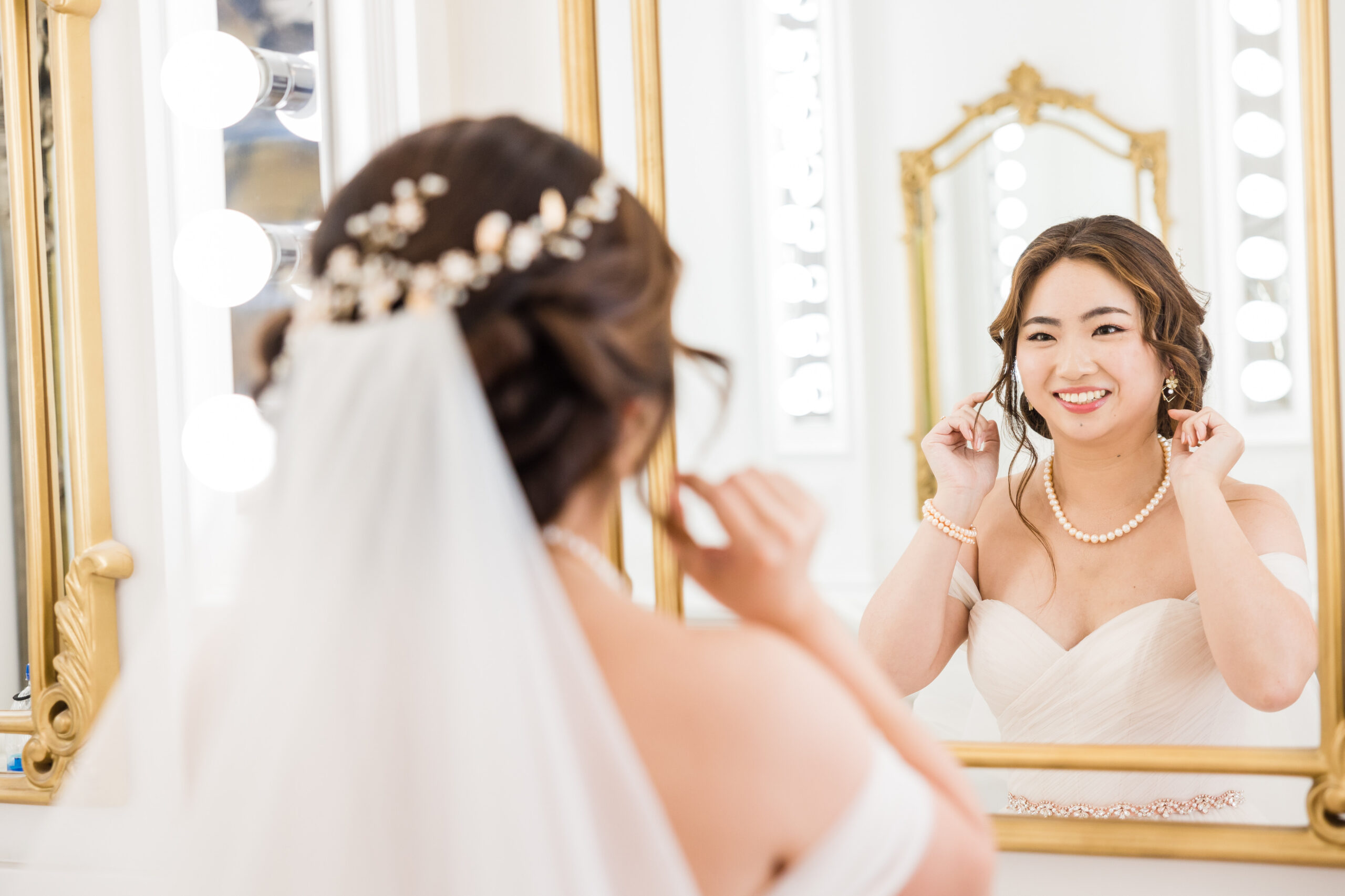 bride smiling at her reflection on the mirror getting ready for her wedding day