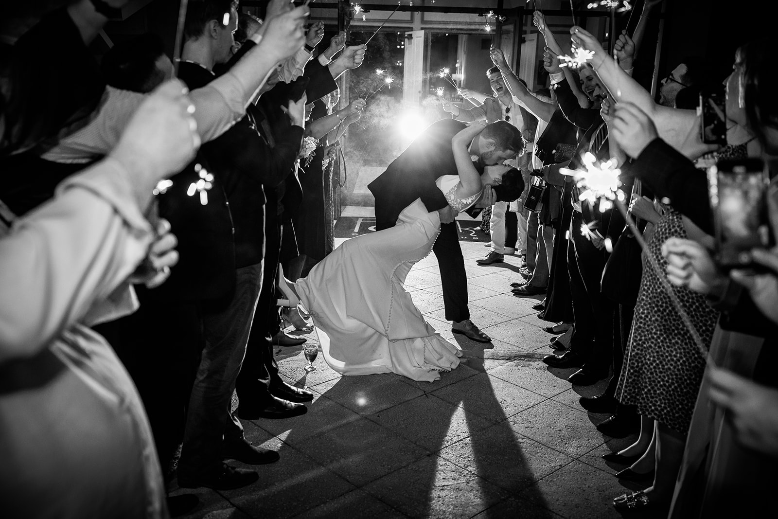 groom dips his bride and kisses him in a sparkle tunnel