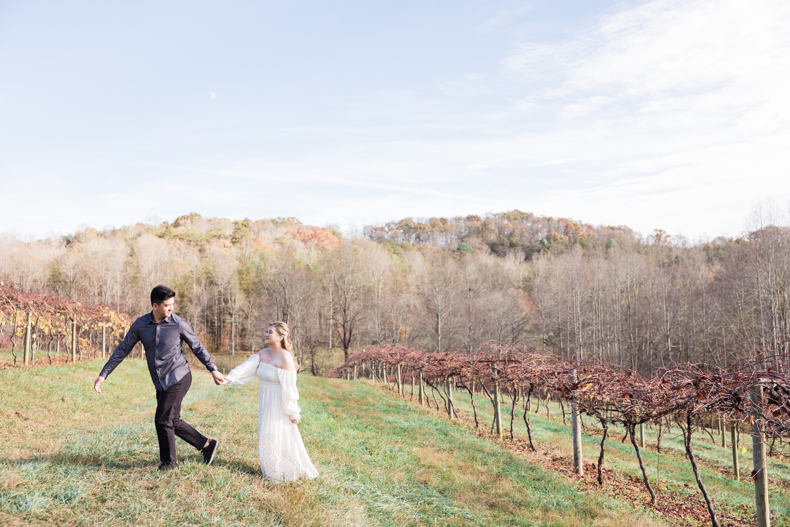 bride and groom walk in a vineyard while holding hands